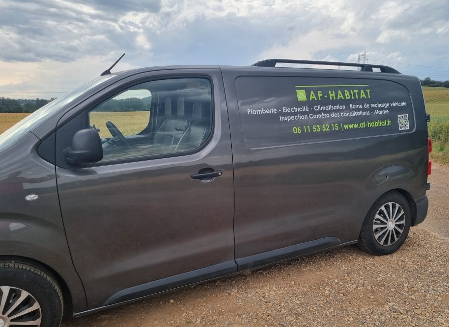 Véhicule Véhicule utilitaire gris avec un logo affichage AF-HABITAT de contact sur le côté.
